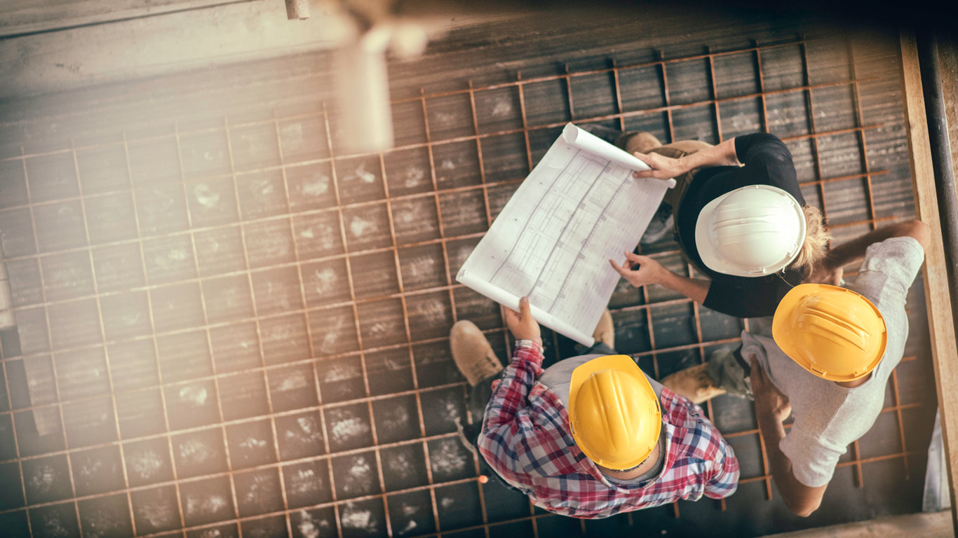 Construction workers review blueprint showing the importance of solid sales foundations