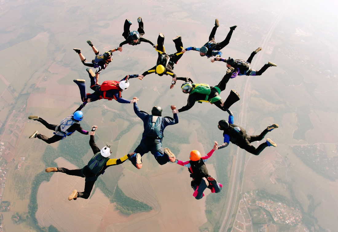 A group skydives together, representing the importance of teamwork between sales and marketing departments.